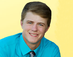 male student wearing a blue shirt and tie smiling