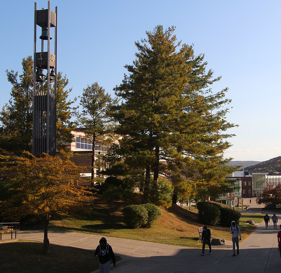 view of center of campus, bell tower, tree, few students walking