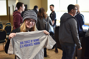 student wearing a hat holding up a t-shirt