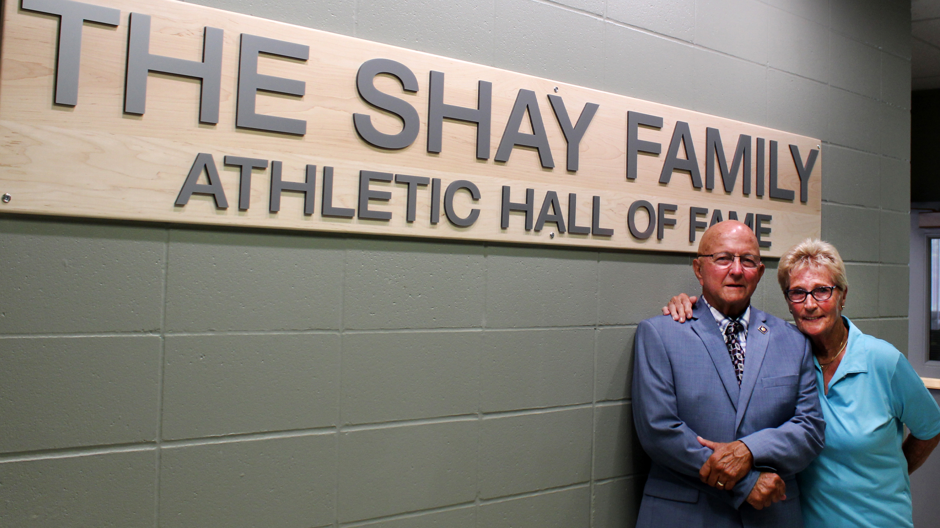 Jon and Linda Shay near The Shay Family Athletic Hall of Fame sign.