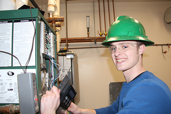 student with green hard hat on working on some wiring