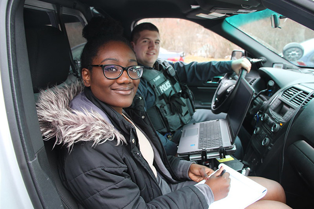 female student sitting in car with police officer