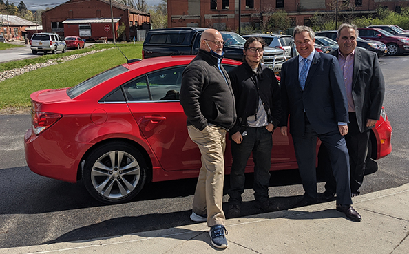 Damian in front of a red car with three other men