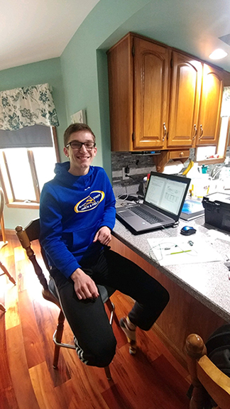 student sitting at kitchen counter with laptop