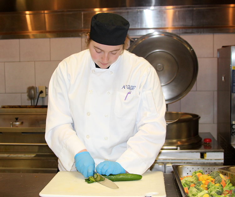 A culinary arts student works in the kitchen