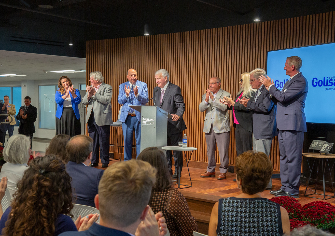 Tom Golisano stands on stage 