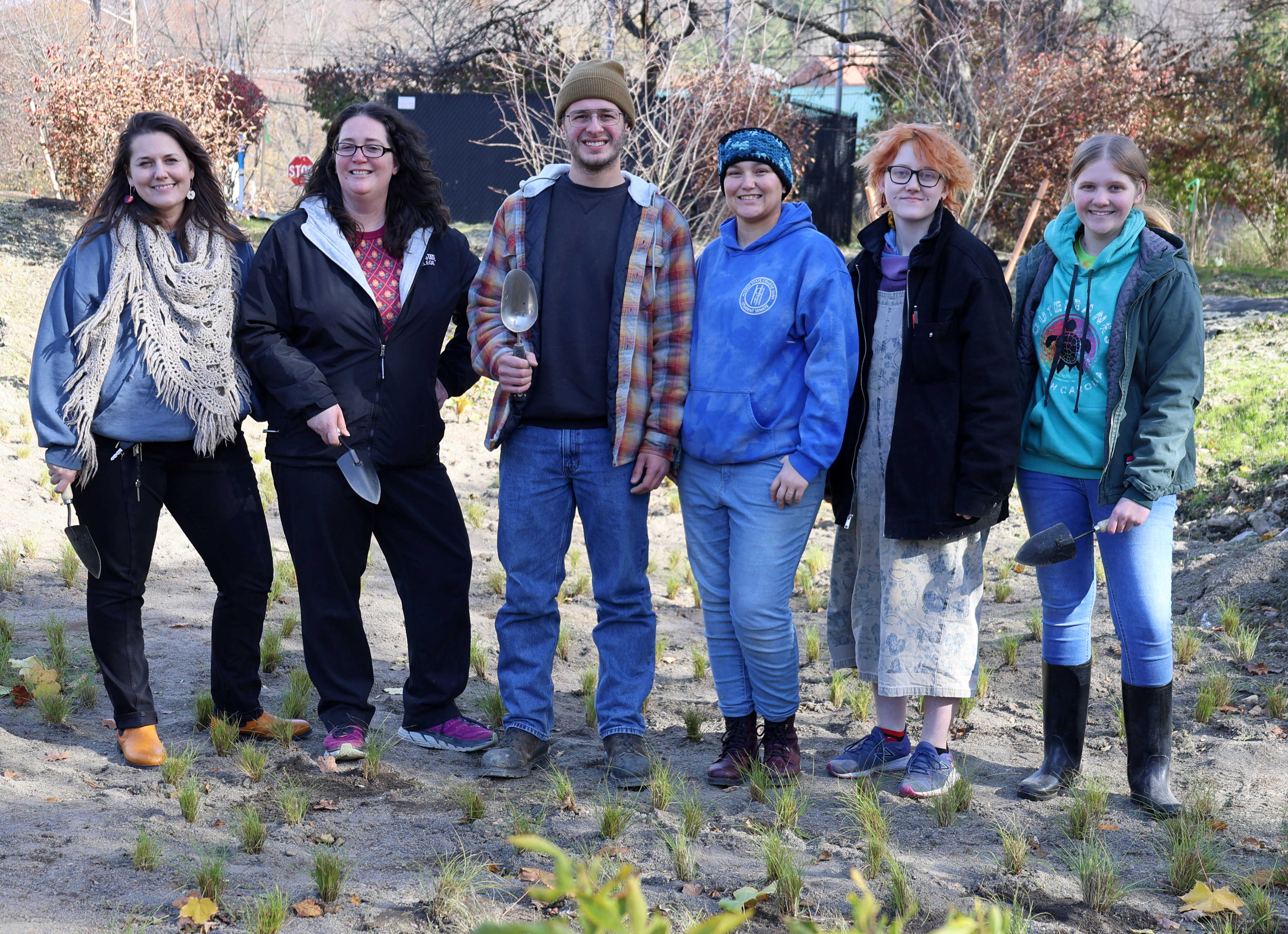 Faculty, staff, and students plant new grasses in a retention pond.