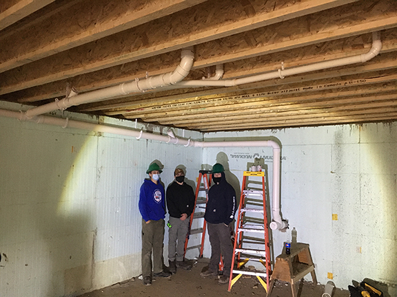 students standing in a basement with piping on ceiling