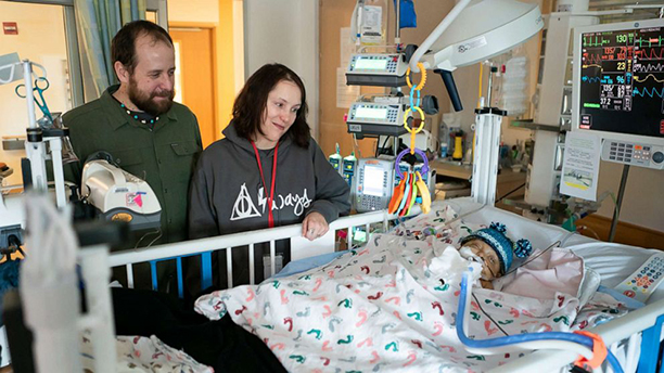 parents near hospital bed where baby lying in