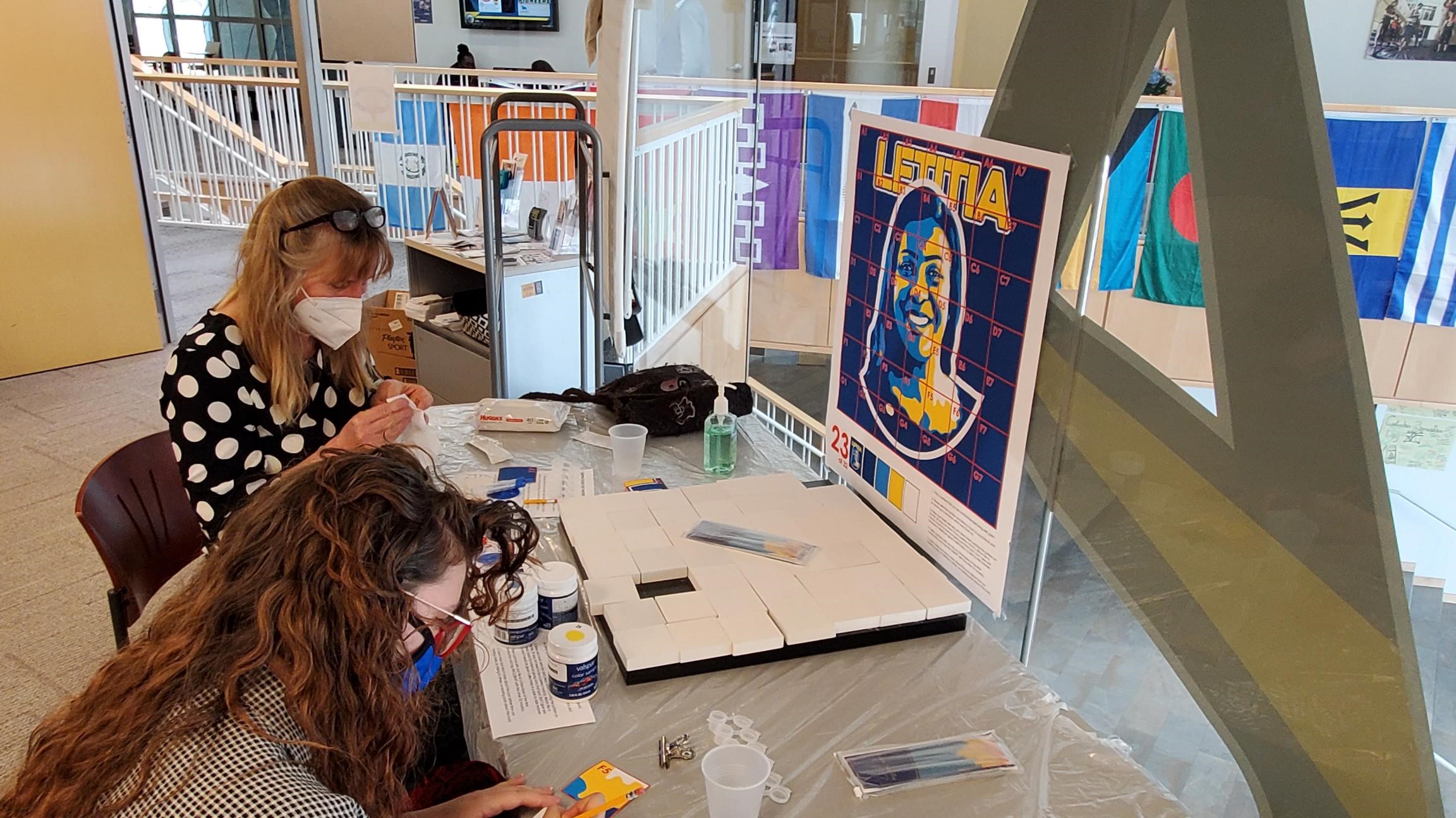 Provost Kristin Poppo and student Molly Lockwood prepare to paint segments of a mural of Letitia James.