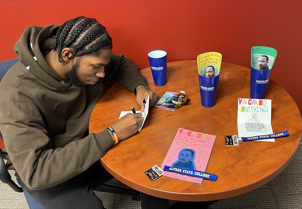 Student Daniel Jean sits at a desk writing a dream card