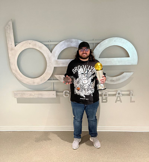 student standing holding some trophies