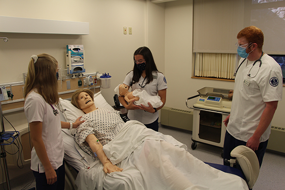 students standing around a nursing bed in a lab setting