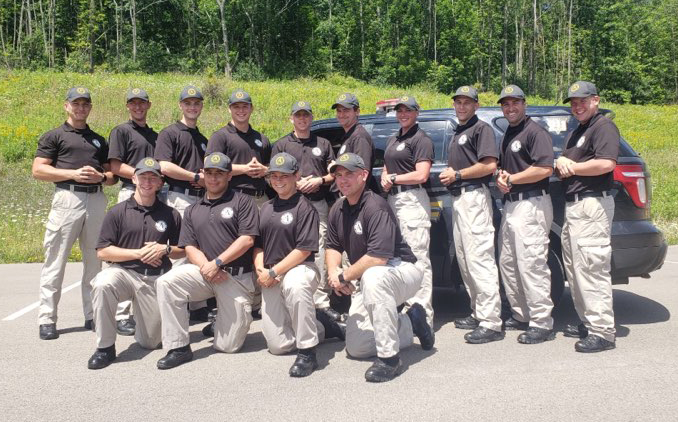 2020 recruits of Alfred State College’s Police Academy standing in front of a vehicle, all wearing tan pants and a black shirt