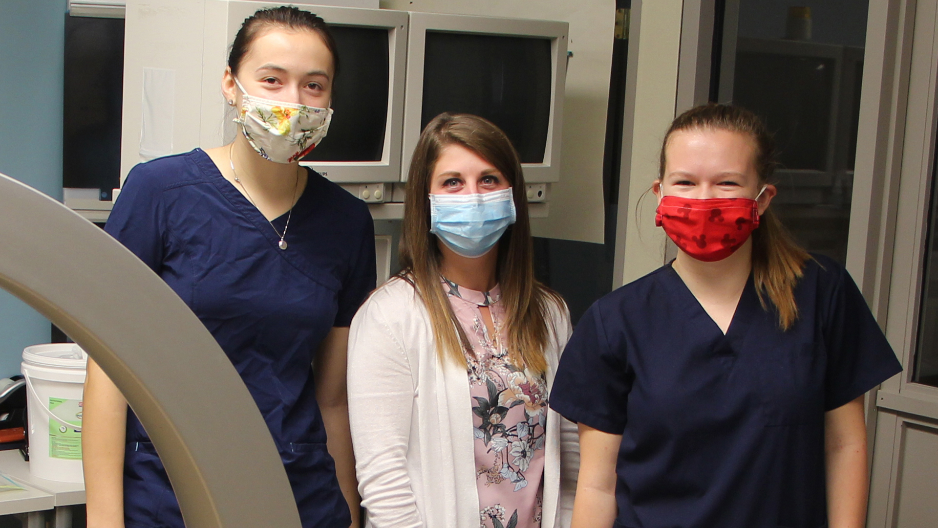 Rad tech students and teacher in masks near C-arm machine