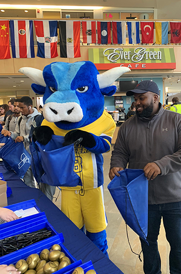 ox mascot and male holding blue bags open in SLC