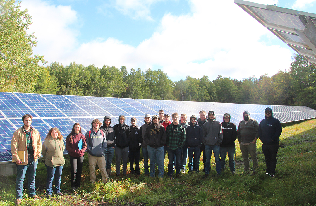 Tyler Uebelhoer stands with a class of Electrical Construction and Maintenance Electrician students at Alfred Community Solar after showing the class the set-up of the new Buffalo Solar project.