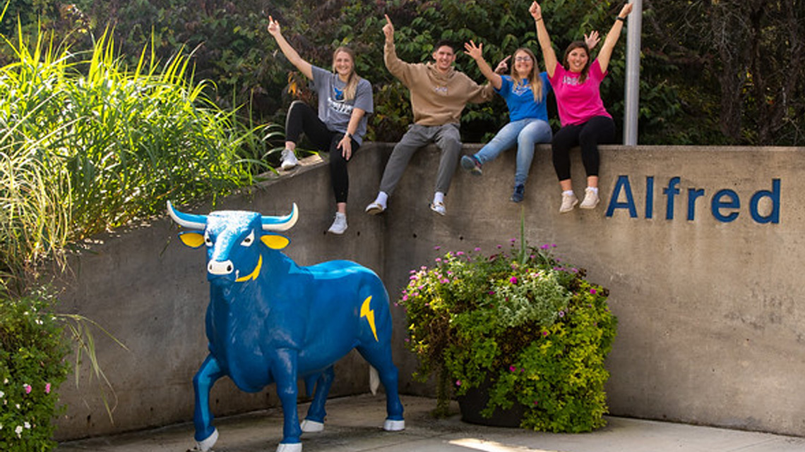 Photo of 4 ASC students posing at the main entrance for Alfred State