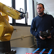 Trentin Barber holding a remote in front of piece of equipment