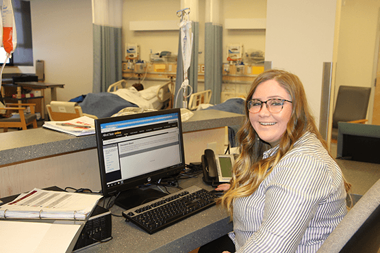 Raeha sitting at a desk with laptop in a hospital setting