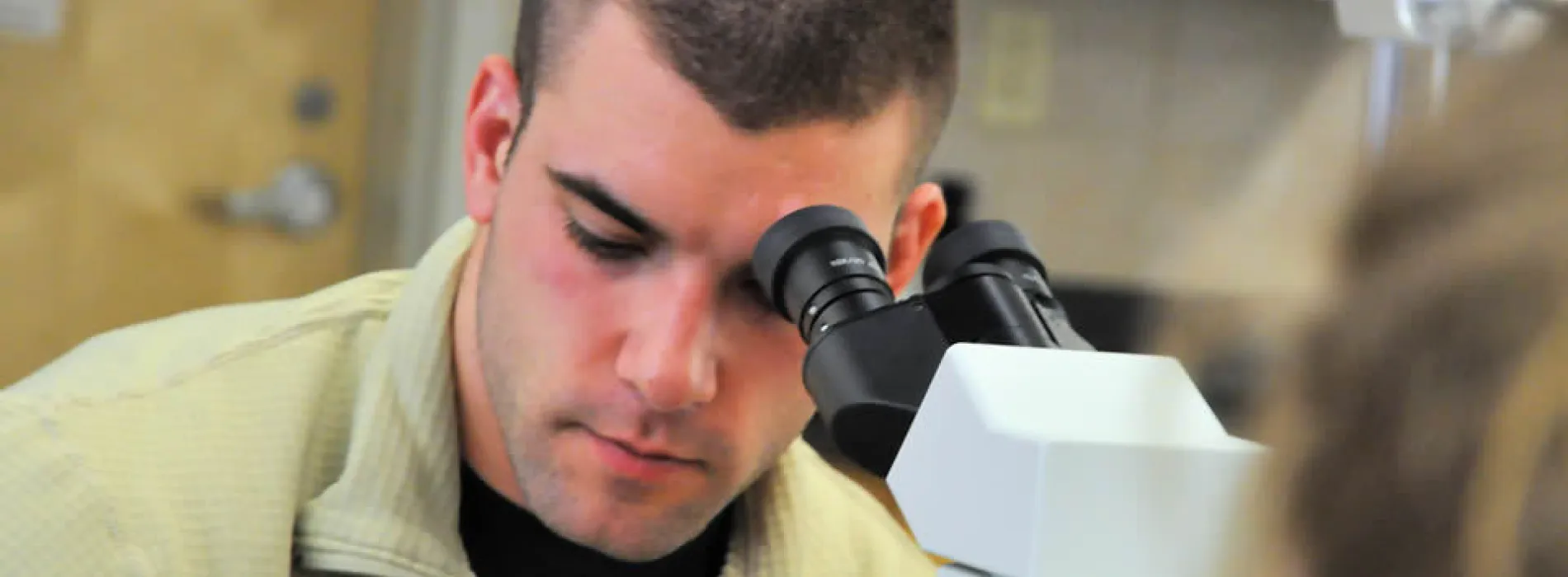 male student in front of a microscope
