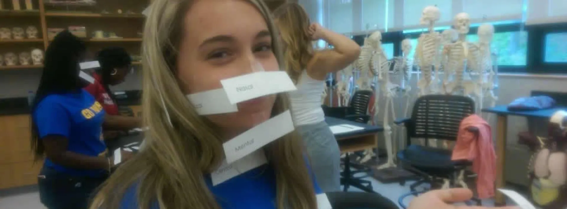 female student with white pieces of paper taped to her face