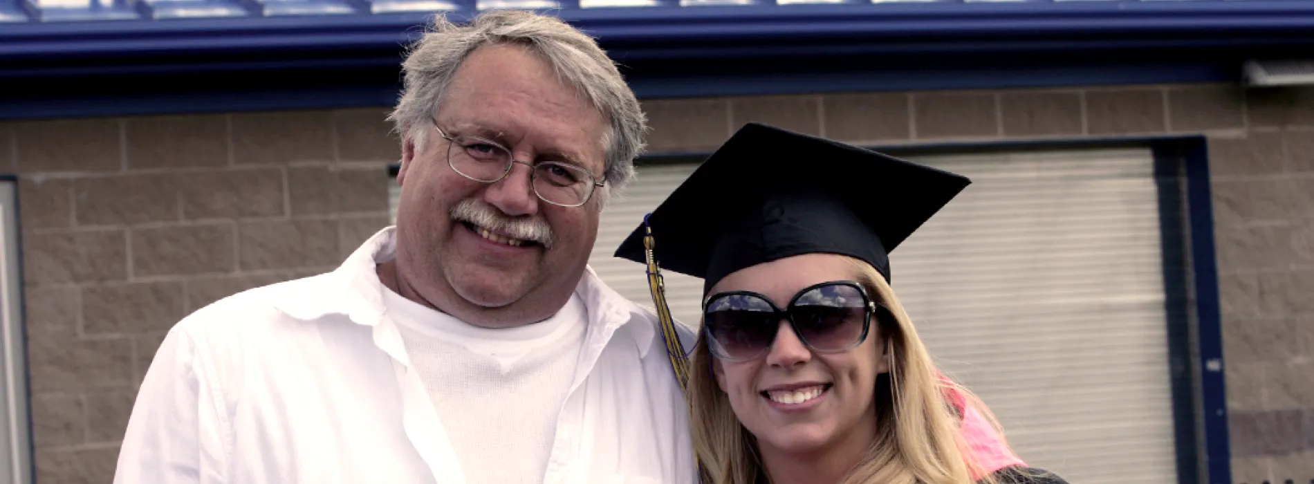 father and daughter, daughter wearing commencement cap and sunglasses