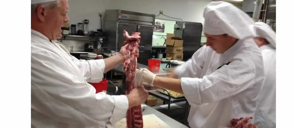 student and instructor cutting up meat