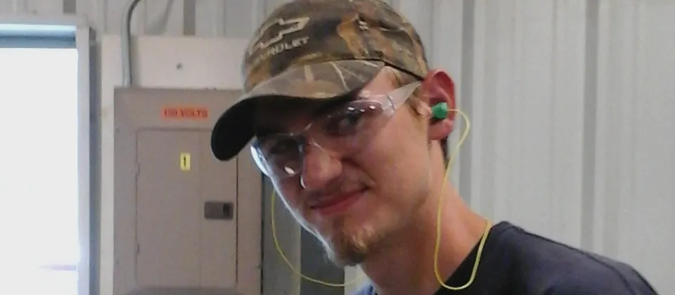 male student wearing safety glasses, a hat, and ear plugs