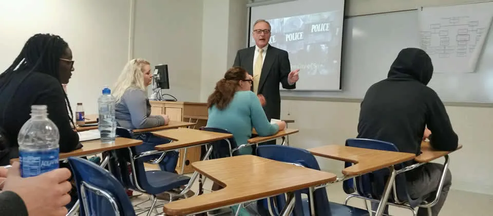 professor with students sitting at desks in a classroom