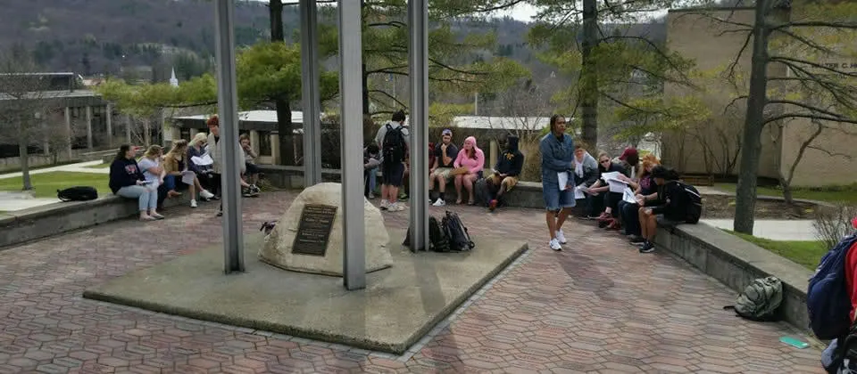 students sitting down in front of the bell tower