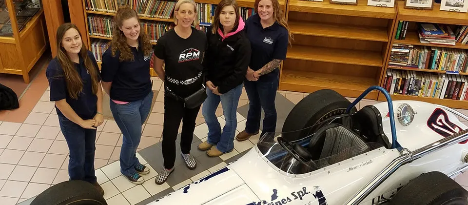 four female students standing with a female race driver