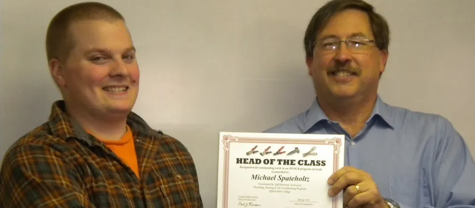 instructor with student holding a certificate that says 'head of the class'