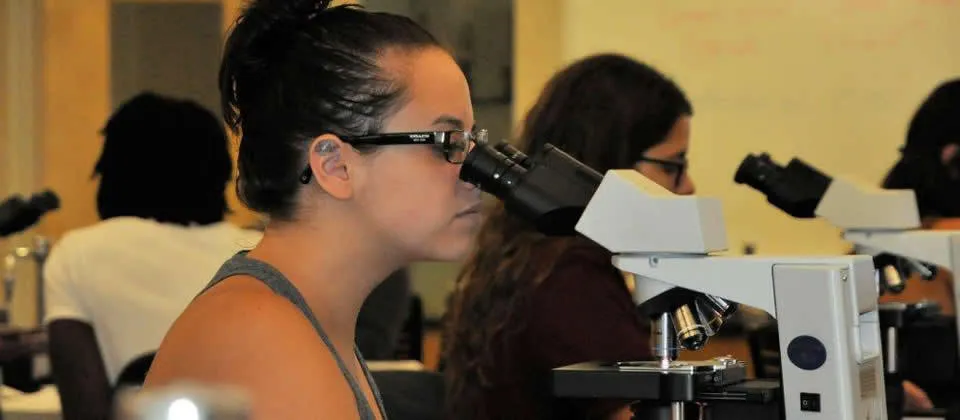 female student looking in microscope
