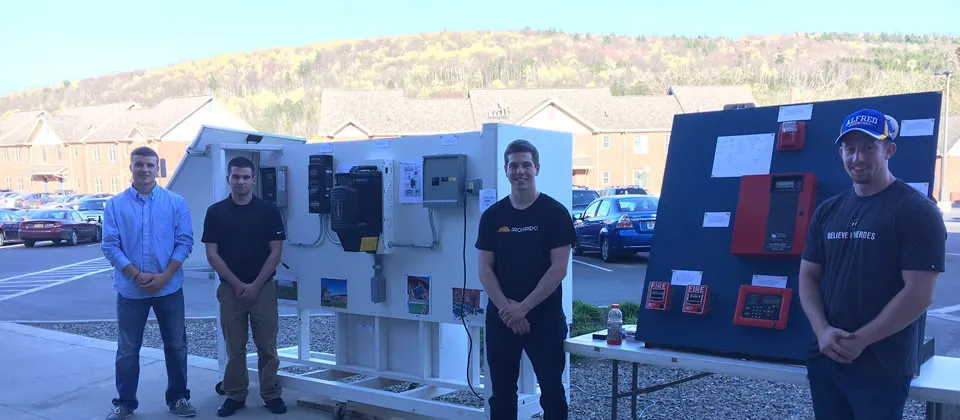 students standing in front of their projects at student showcase