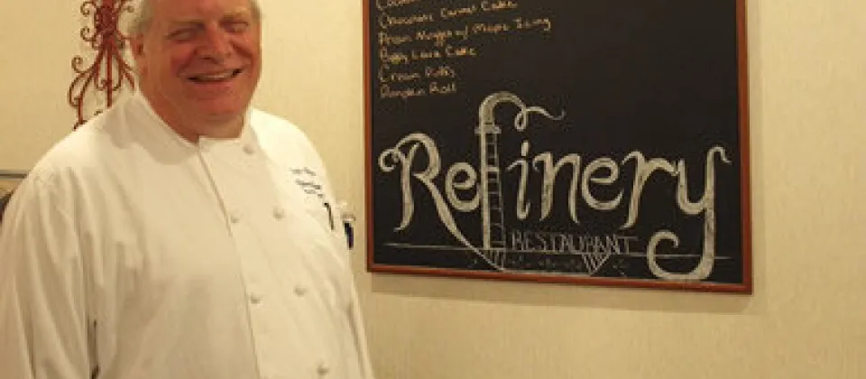 chef near the chalkboard sign that says Refinery