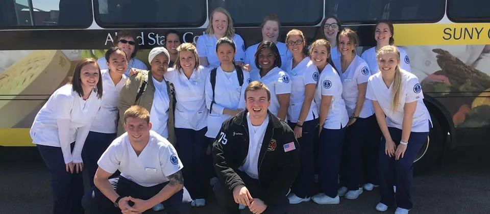 several nursing students standing in front of a bus