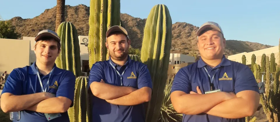 three students standing with their arms folded in front of cactus