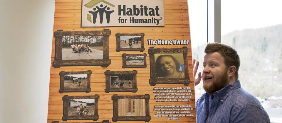 student presenting a poster board about Habitat for Humanity