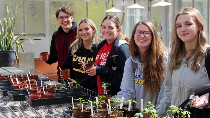 Students smiling in a greenhouse