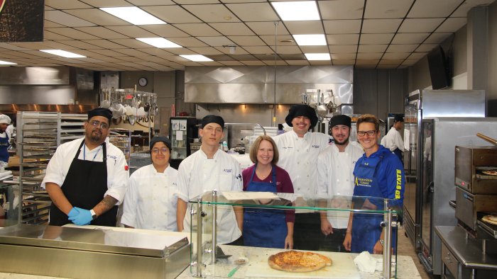 Kishan Zuber and Carrie Cokely learn new skills from Culinary Arts students.