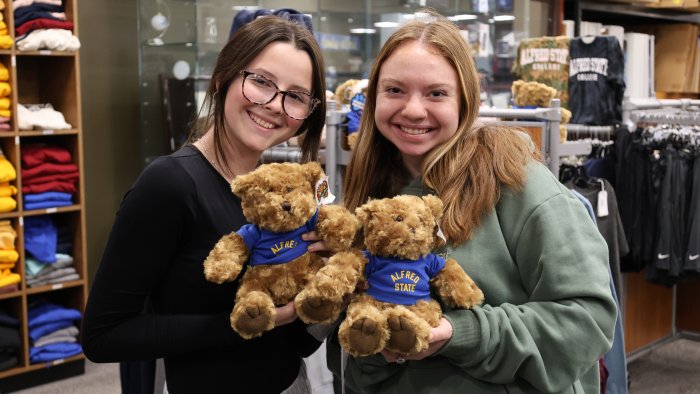 Students posing with Alfred State teddy bears at the Campus Store.