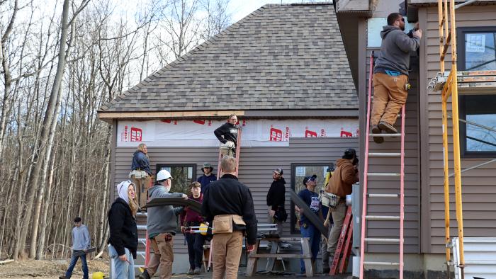 Students put siding on house in Wellsville.