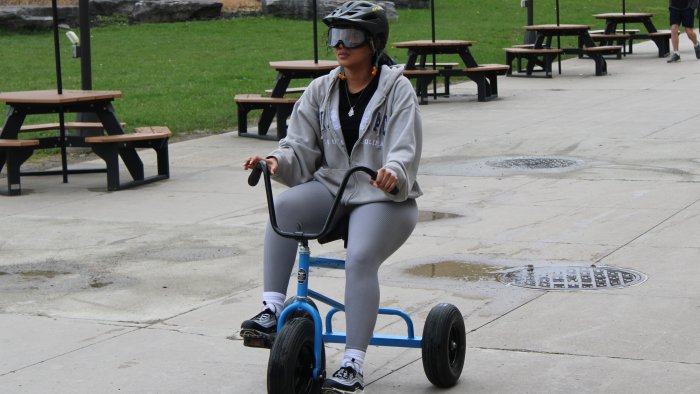 Students rides a tricycle with drunk goggles on.
