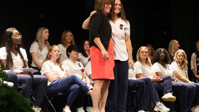 Student poses with faculty at Nursing Pinning Ceremony
