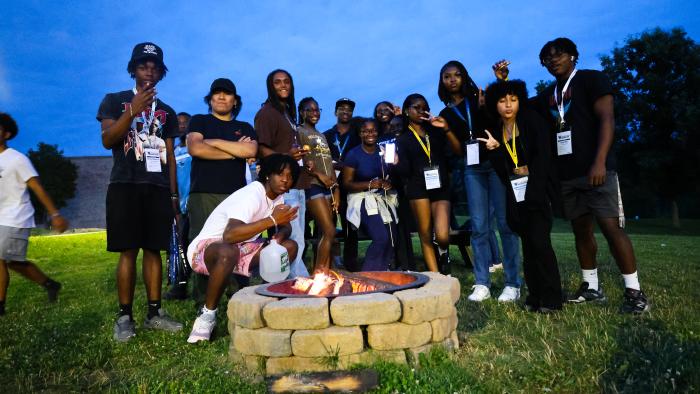 Incoming students warm up by a bonfire