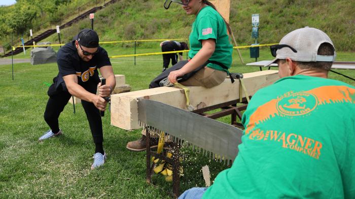 Student tries cutting lumber at Student Activities Fair
