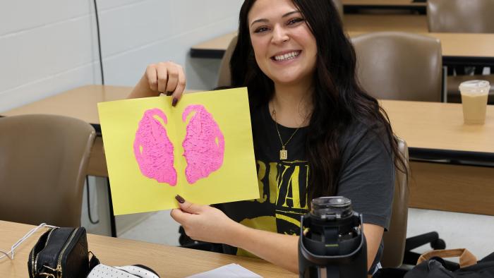 Applied Psychology student poses with her work