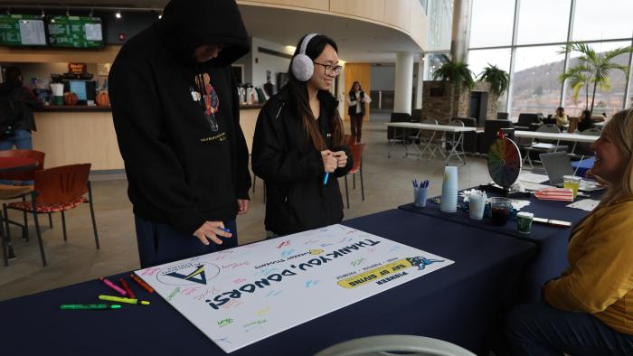 Students sign Day of Giving thank you poster