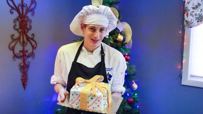 Culinary student poses with holiday cake